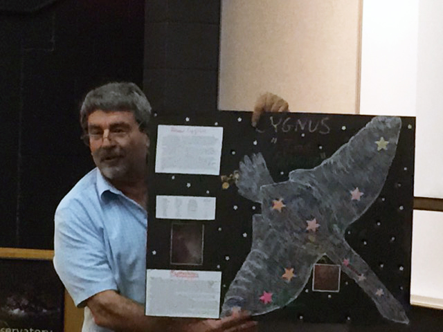 Al Washburn shows a poster of Cygnus made by one of his students.