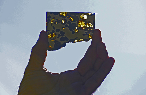 Photo by Alan Chaniewski
Meteorite Man, Al Washburn holds up a thin piece of meteorite that you can actually see through.
Funny, it looks like a cut out of Connecticut!
